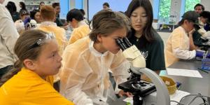 Campers and volunteer with a microscope.